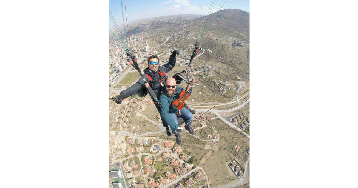 Nervous Teacher Plays Violin To Distract Himself During First Paragliding Flight